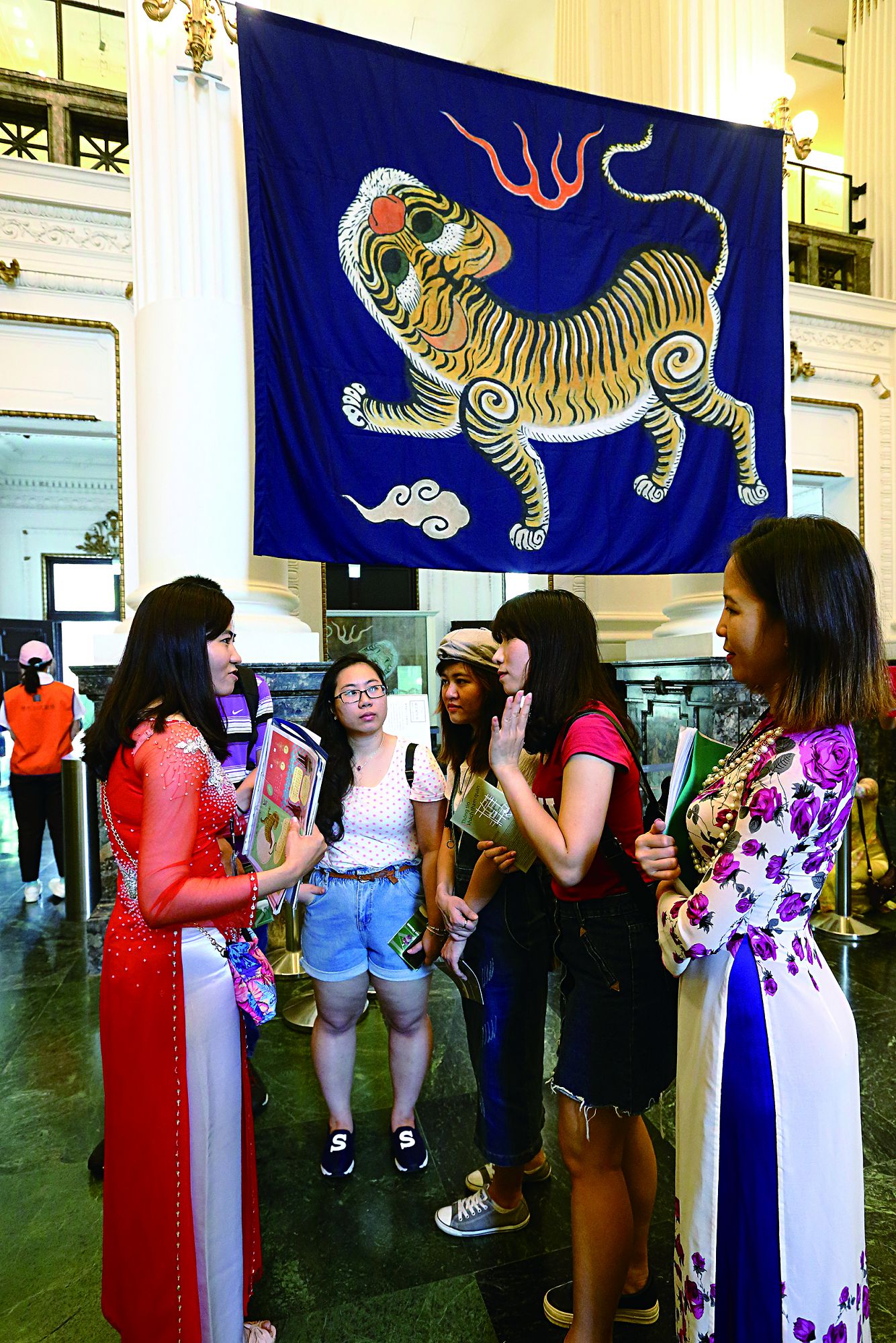 新住民服務大使陳秀萍為越南的朋友解說臺博館鎮館之寶「藍地黃虎旗」的故事。